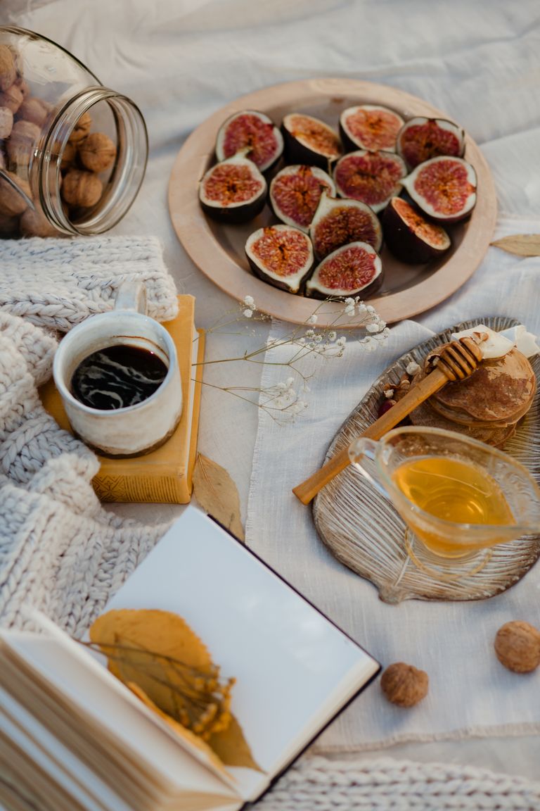 Warm and inviting rustic picnic setting with figs, honey, and cozy textiles, perfect for autumn gatherings.